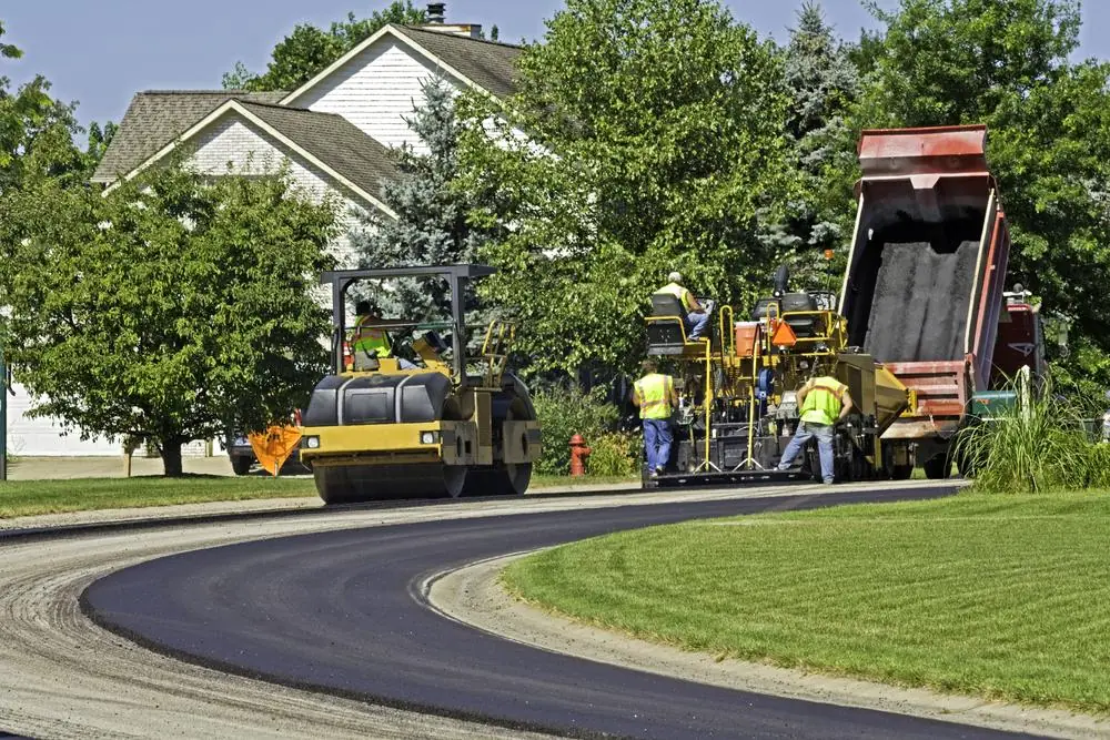 Paving crew and roller working on a curved residential roadway